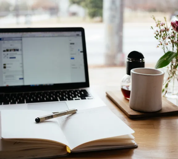 laptop with planner and mug on table