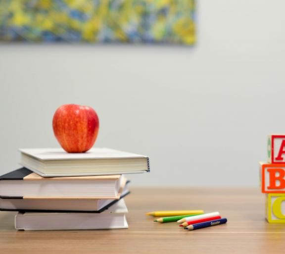 apple on stack of books on a desk