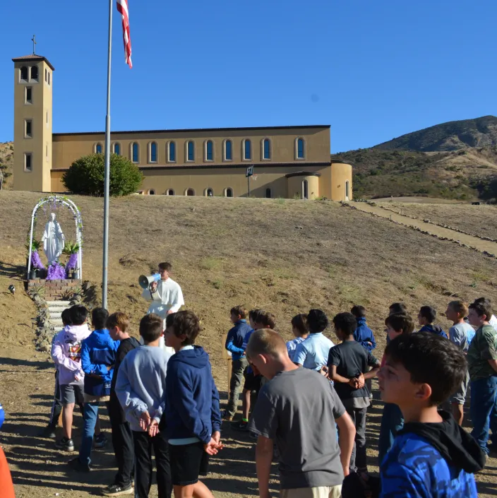priest speaking to children outside