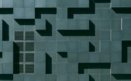 Dark teal wall with various cement blocks jutting outwards creating a horizontal and vertical pattern